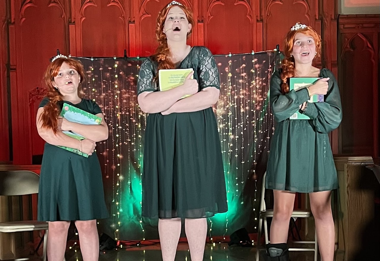 Three young performers in costume on stage